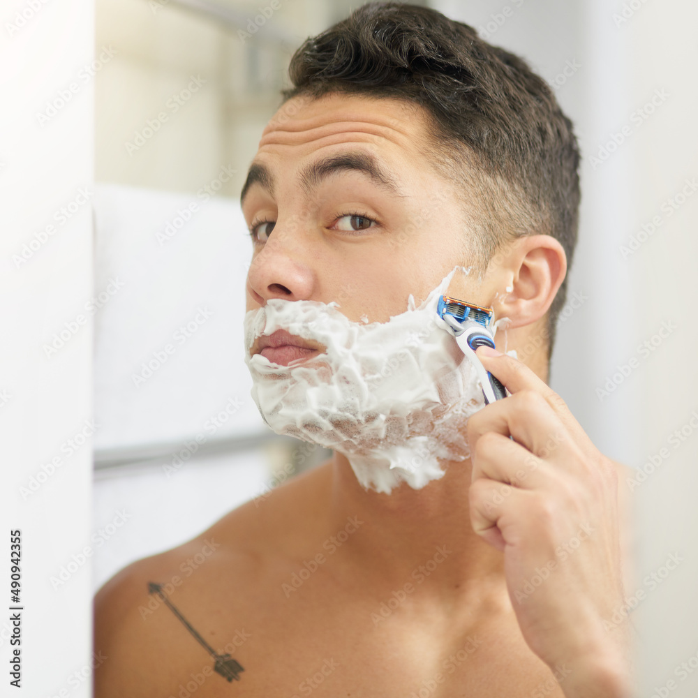 Keeping a clean face. Cropped shot of a young man shaving his beard.
