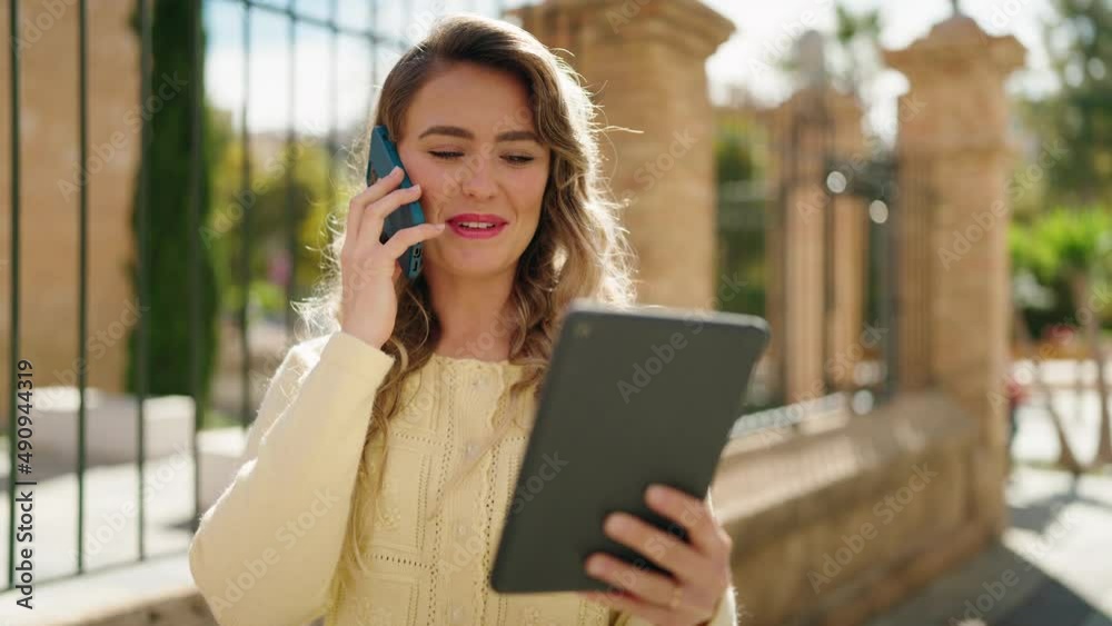 Young blonde woman talking on the smartphone using touchpad at street Young blonde woman talking on the smartphone using touchpad at street