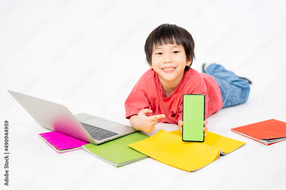 Portrait of Happy asian boy holding a phone in his hands with a green screen on floor with with laptop and books isolated on white background with copy space, Education and learning with technology Portrait of Happy asian boy holding a phone in his hands with a green screen on floor with with laptop and books isolated on white background with copy space, Education and learning with technology