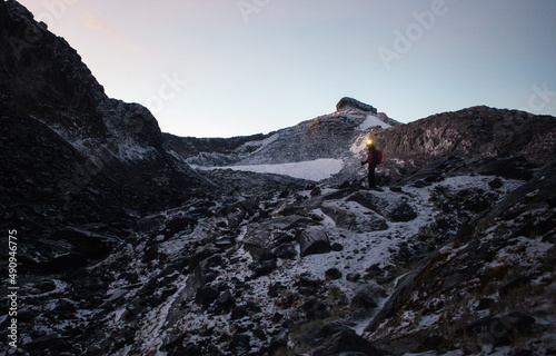 Female hiker facing camera with warm head lamp glow while in the midst of epic glacier landscape