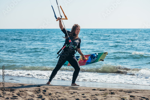 Woman holding kiteboard and going into the water photo