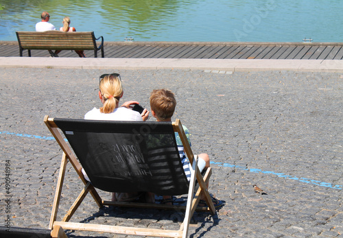 A woman and her child sitting outside in a chair by a lake on a sunny summer day photo
