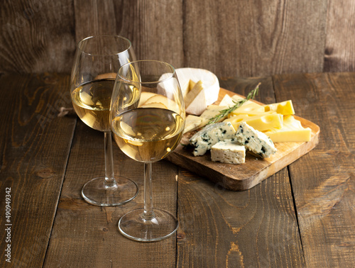 Cheese and a glass of white wine on a wooden background. Different cheeses on a wooden board. Cheese set.