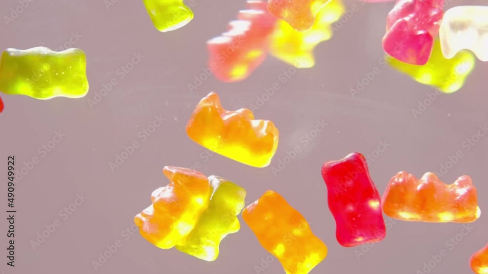red, orange, yellow gelatin candies, drugfilled gelatin bears falling on the table from above