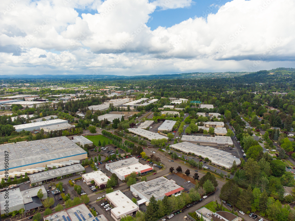 Shooting from a drone. Small town. Roofs of small one-story houses. Lots of greenery. Mountains are visible in the distance. Asphalt roads. There are many white clouds in the sky. Ecology, map.