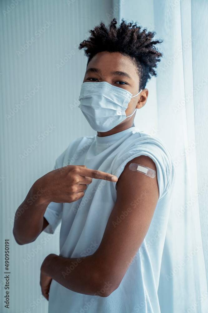 Leinwandbild Motiv - Blue Planet Studio : African American teenager showing COVID-19 vaccine bandage merrily in concept of coronavirus vaccination program to vaccinate citizen .