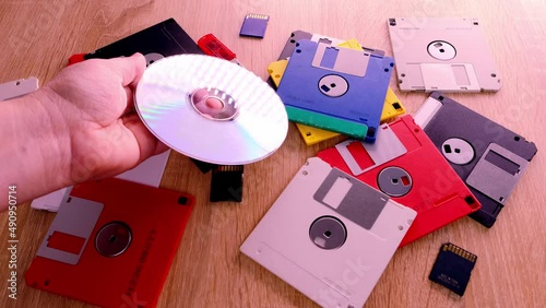 vintage retro electronic data storage devices from the 80s, 90s, cd disk, flash drives scattered on table. Stack of floppy disks, pendrive and hard disk in grey, black, blue, yellow, red, white photo