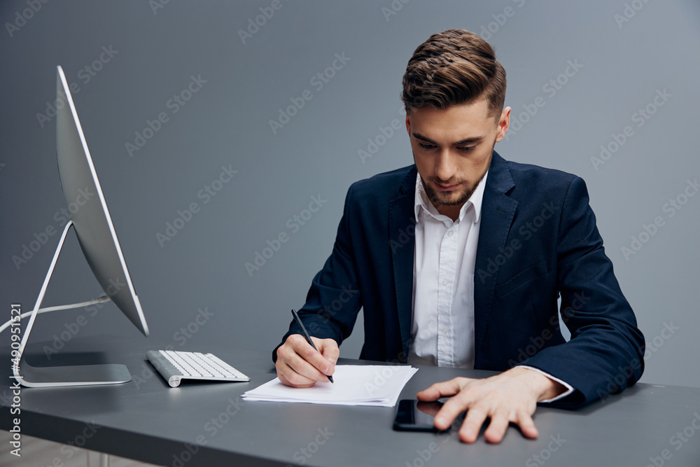 a man in a suit sitting at a desk in front of a computer with phone executive a man in a suit sitting at a desk in front of a computer with phone executive