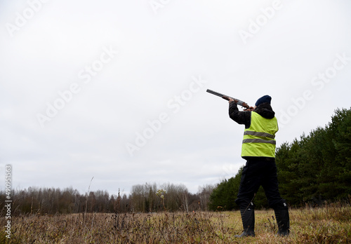 Hunter while hunting a wild bird. Hunters with gun and rifle on hunting in the fall season. Hunters during hunting in forest. The hunter shoots the birds in the sky.