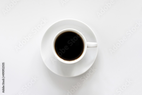 White cup of coffee on a saucer, on a white background, top view