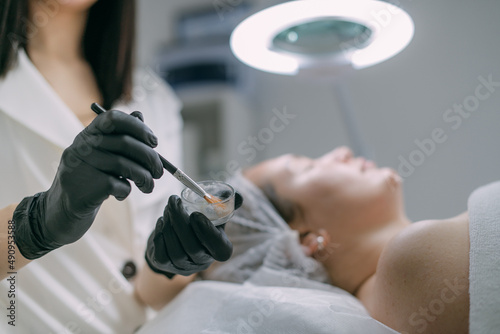 Cosmetologist and dermatologist makes a moisturizing, rejuvenating woman lying patient in a beauty salon.