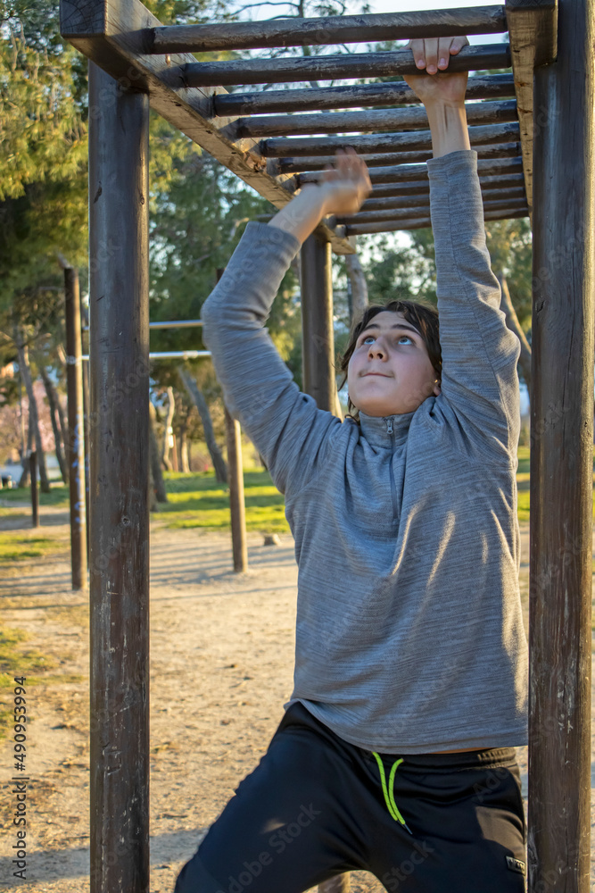 Fototapeta premium Teenage doing exercise in a park with parallel bars