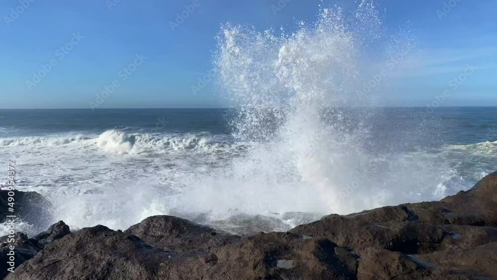 Huge ocean wave crashes into the air after smashing into rocky Oregon coastline at high tide.
