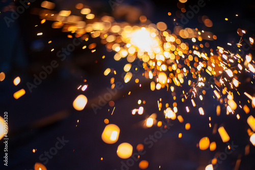 Sparks from grinding metal. Steel processing in workshop. Lights in dark. Production of parts. Cutting became grinder.