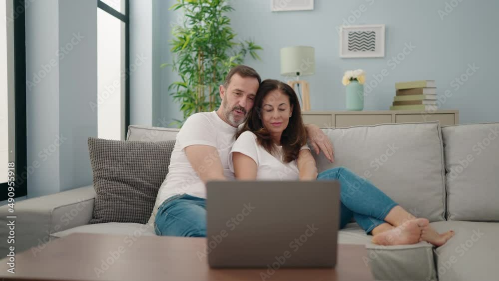 Man and woman couple watching movie sitting on sofa at home Man and woman couple watching movie sitting on sofa at home