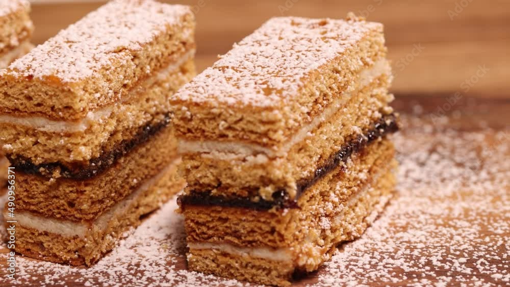 Traditional homemade Romanian Honey Layered Cake with plum jam and semolina cream also called Albinita or Dulcineea. Panning shot of cut portions of cake. Traditional homemade Romanian Honey Layered Cake with plum jam and semolina cream also called Albinita or Dulcineea. Panning shot of cut portions of cake.