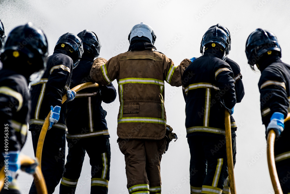 A team of firefighter work toghether to extingish a fire while their are applying water. A team of firefighter work toghether to extingish a fire while their are applying water.