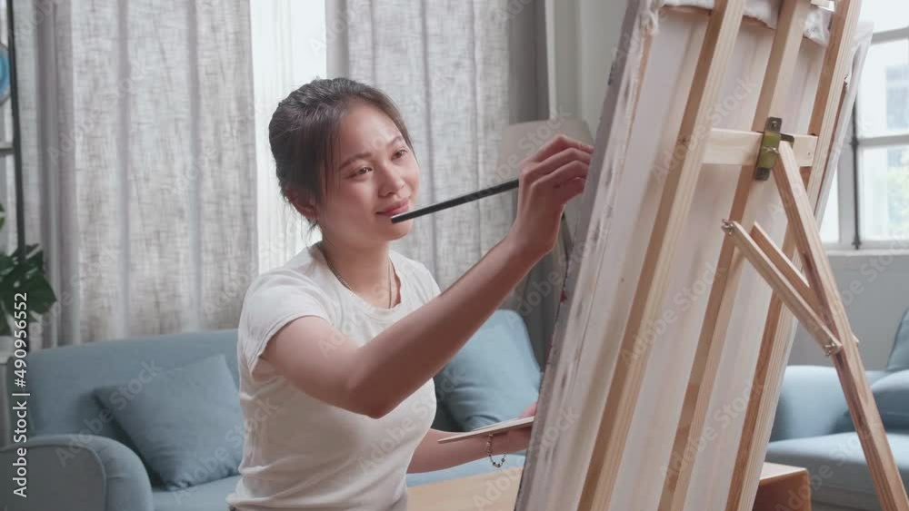 Asian Artist Girl Sitting On Round Wooden Chair Without Backrest Holding Paintbrush And Mixing It With Colour Before Painting On The Canvas
Asian Artist Girl Sitting On Round Wooden Chair Without Backrest Holding Paintbrush And Mixing It With Colour Before Painting On The Canvas