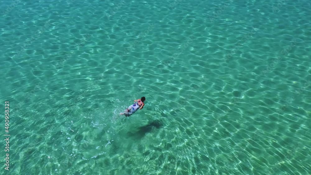 Beautiful woman in colorful dress swimming in blue clear empty sea. Vacation summer concept Beautiful woman in colorful dress swimming in blue clear empty sea. Vacation summer concept