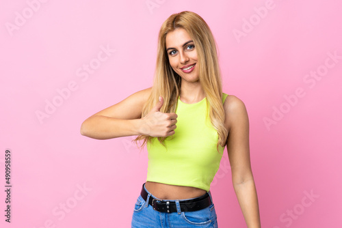 Young Uruguayan blonde woman over isolated pink background giving a thumbs up gesture © luismolinero