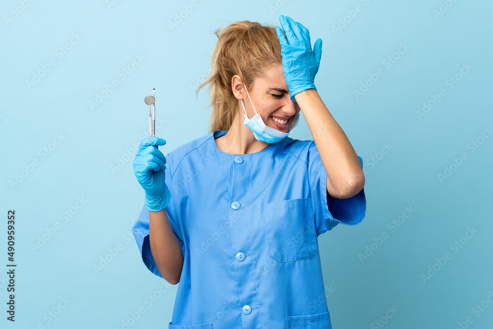 Young woman dentist holding tools over isolated blue background having doubts with confuse face expression Young woman dentist holding tools over isolated blue background having doubts with confuse face expression