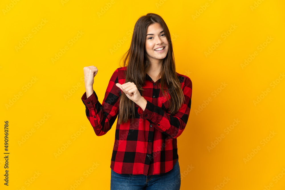 Teenager Brazilian girl isolated on yellow background pointing to the side to present a product Teenager Brazilian girl isolated on yellow background pointing to the side to present a product