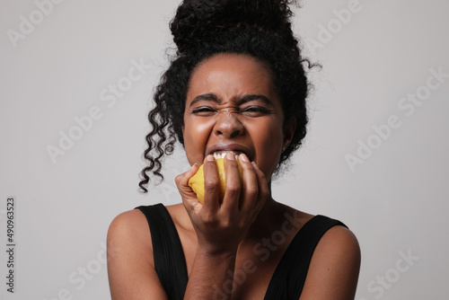 Cropped photo of woman posing with lemon on white wall for skin and body care
