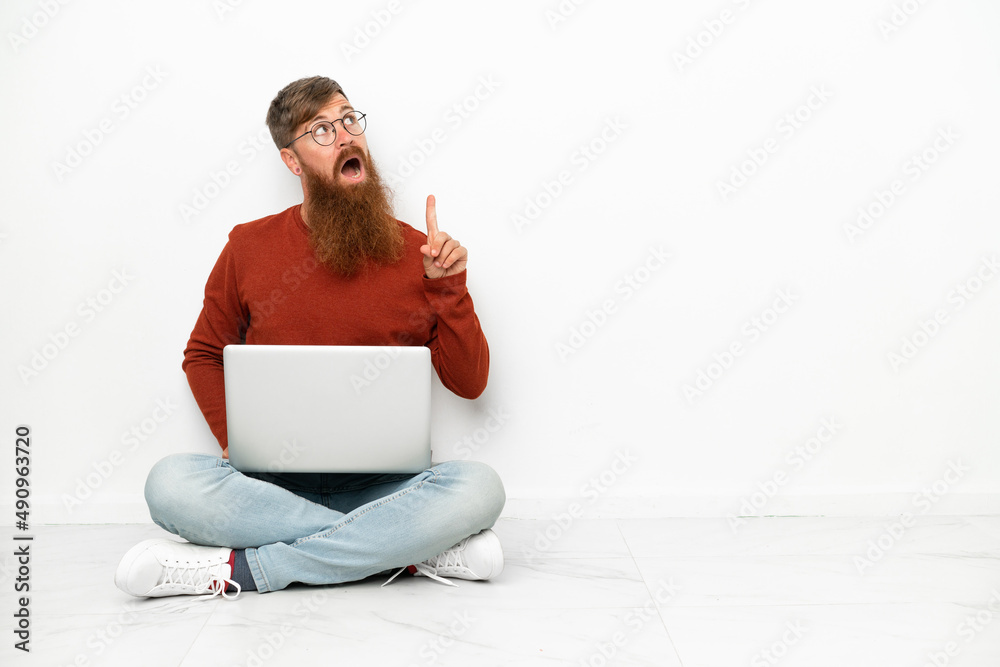 Young reddish caucasian man with laptop isolated on white background thinking an idea pointing the finger up Young reddish caucasian man with laptop isolated on white background thinking an idea pointing the finger up