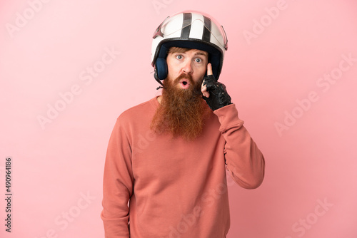 Young reddish caucasian man with a motorcycle helmet isolated on pink background thinking an idea