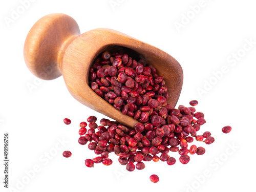 Sumac seeds in wooden scoop, isolated on white background. Whole dry Rhus berry.