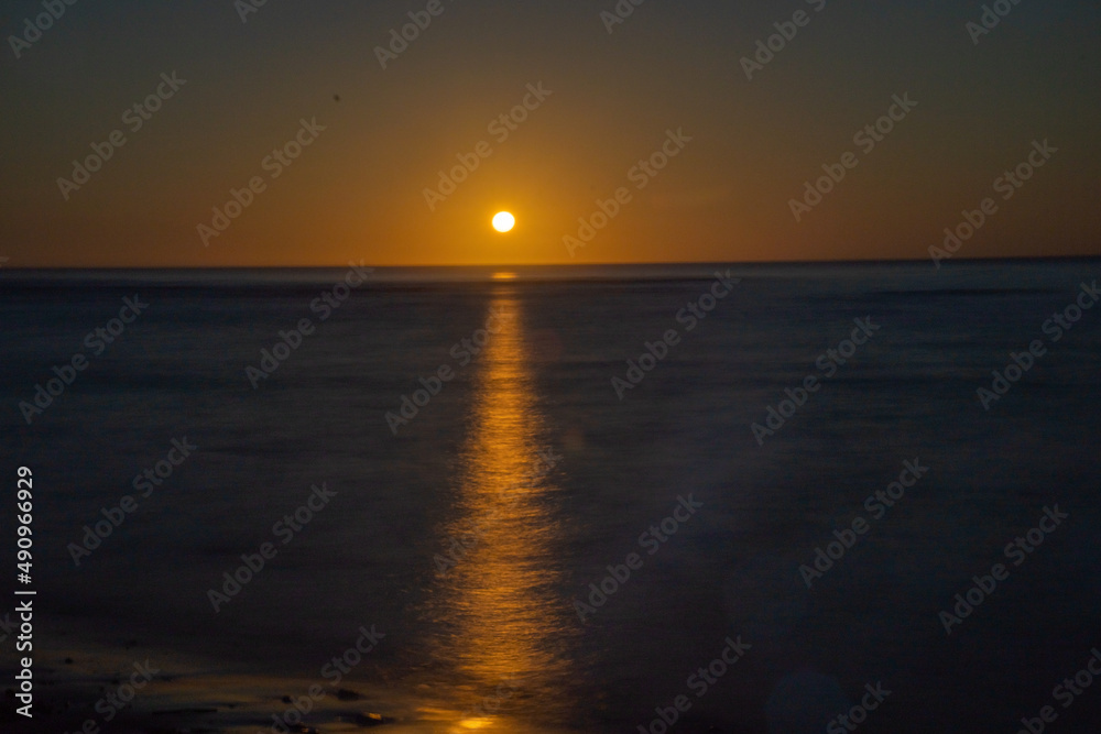 Sunrise just on horizon starts to illuminate and warm the air over sea of Tokomaru Bay New Zealand.