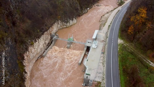 River flood, aerial drone view. Flooded small hydropower plant. Water floods and landslide during heavy rain. Raging river. photo