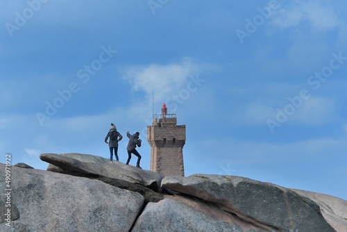 A couple on a rock in front of an headlight jn Brittany France photo