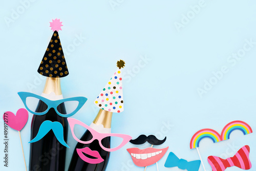 Carnival background with party props, masks, and champagne on a light blue background. Carnival concept, purim background. Top view, copy space © Laima Gri
