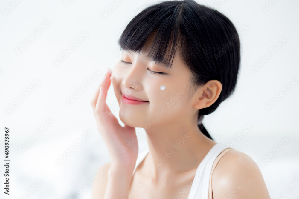 Beautiful young asian woman happy applying cream or lotion with moisturizer to skin on face, beauty asia girl applying skincare touch facial with cosmetic makeup, skin care and health concept. Beautiful young asian woman happy applying cream or lotion with moisturizer to skin on face, beauty asia girl applying skincare touch facial with cosmetic makeup, skin care and health concept.