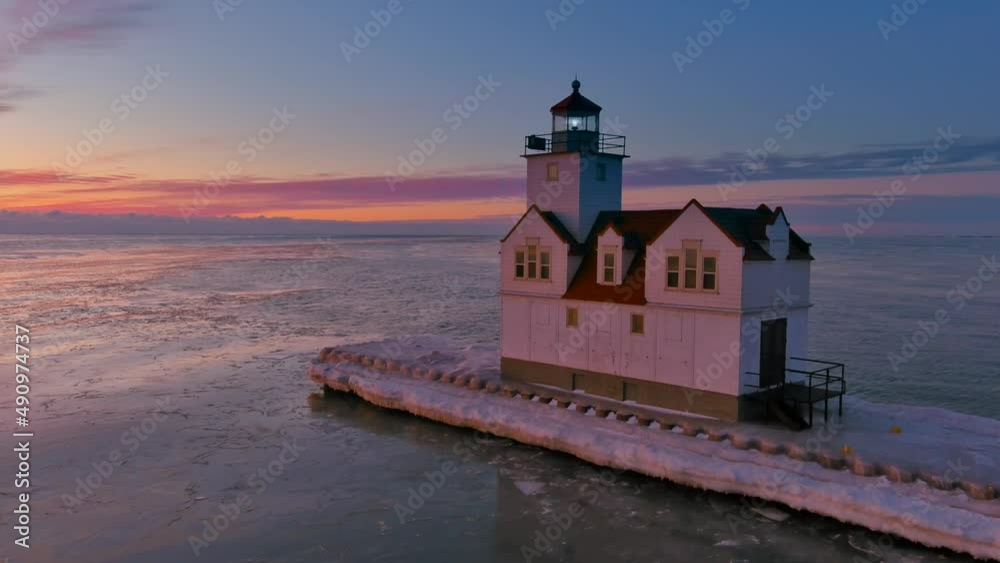 There is amazing beauty in this aerial view of Kewaunee Harbor, clouds on the horizon, waves reflecting the fiery sky, lighthouse beacon alight, Lake Michigan in the Winter just before sunrise. There is amazing beauty in this aerial view of Kewaunee Harbor, clouds on the horizon, waves reflecting the fiery sky, lighthouse beacon alight, Lake Michigan in the Winter just before sunrise.