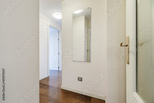 Entrance to a residential home with nook and cranny hallways, white painted walls and parquet flooring