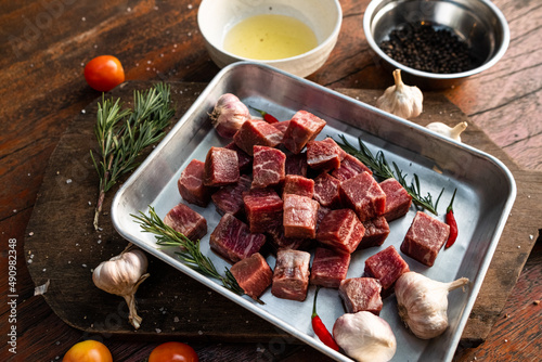 Sliced grilled thai steak served on white plate with grilled sliced lemon, tomatoes, garlic