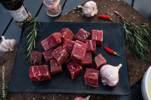 Sliced grilled thai steak served on white plate with grilled sliced lemon, tomatoes, garlic