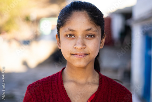 Close up Portrait of a young indian village girl wearing winter clothes and smiling into the camera.