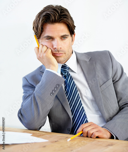 Needing a change in career. Bored young businessman sitting at his desk. photo