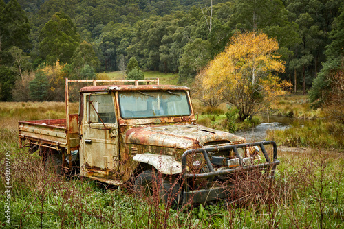 Old vehicle abandoned in the Australia bush near a stream trees and grassland