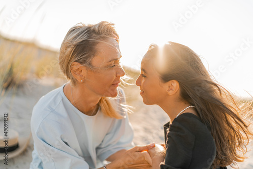 Outdoor   portrait  of beautiful family. Mother and doughter posing on the beach. Warm sunset colors. photo
