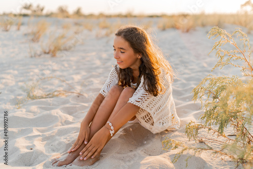 Small girl in stylish boho summer outfit posing on the beach. Warm sunset colors. Wacation and  travel concept. photo