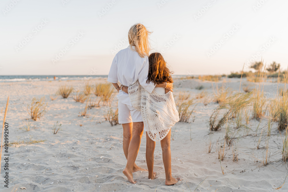 European mom with cute little daughter posing on sunny beach. Wearing light boho  summer clothes. Sunset light. Family vacations concept. foto de Stock |  Adobe Stock