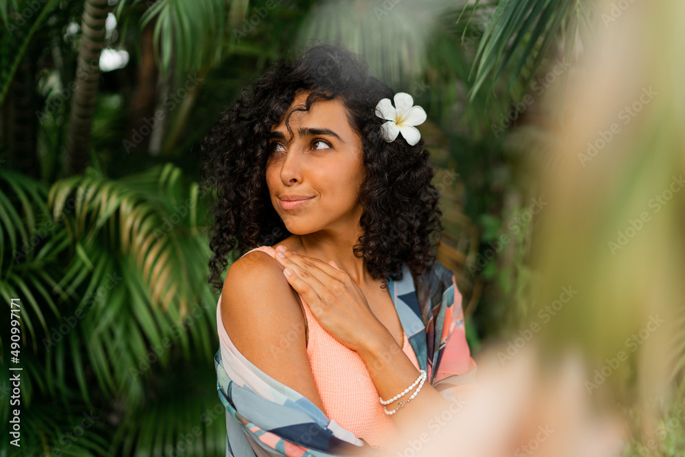 Close up portrait of blissful woman with plumeria flower in hairs after spa in luxury resort. Wearing boho tropical outfit. Close up portrait of blissful woman with plumeria flower in hairs after spa in luxury resort. Wearing boho tropical outfit.