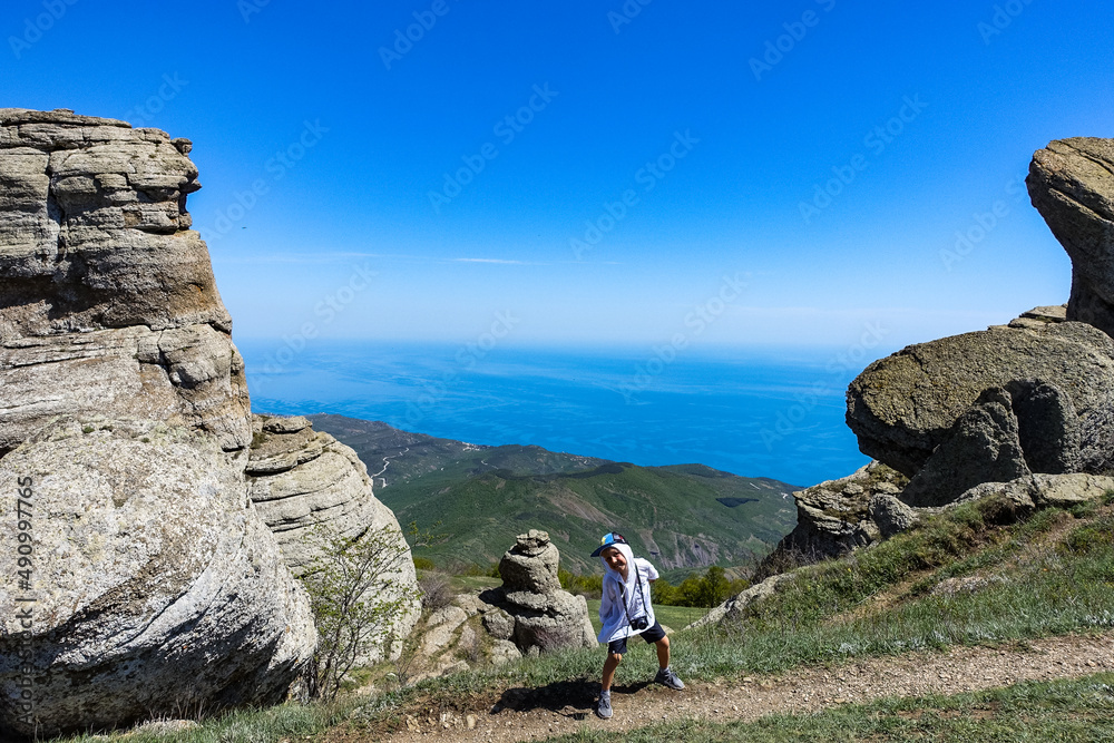 A boy against the background of ancient limestone high mountains. The Valley of Ghosts. Demerji. Crimea.