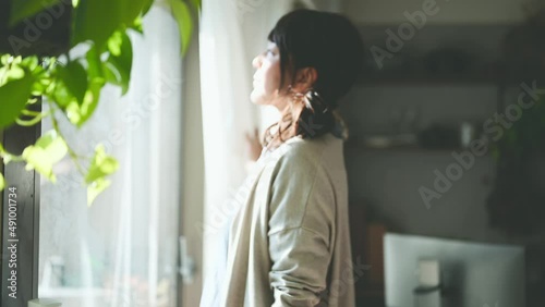 朝、カーテンを開けて伸びをする女性	