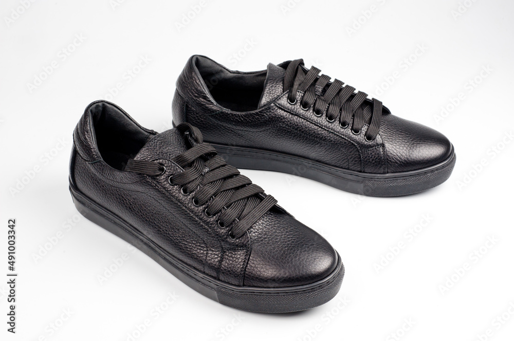 Black imitation leather shoes laced with wide laces. Close-up shot. Black imitation leather shoes laced with wide laces. Close-up shot.