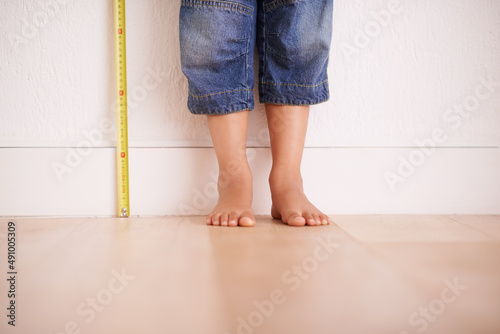 Getting taller by the day. Cropped shot of a young boy standing next to a tape measure. photo